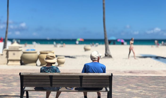 Zwei Leute auf einer Bank bei Strand und Meer