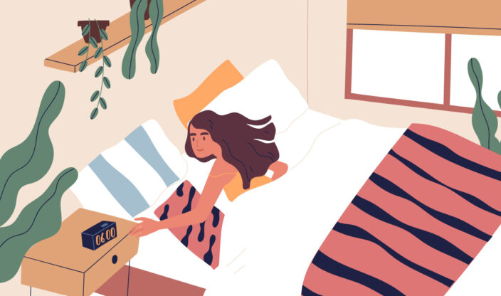 Frau liegt im Bett und macht Wecker aus