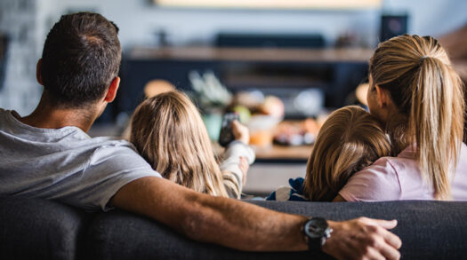 Familie sitzt auf der Couch und schaut fern