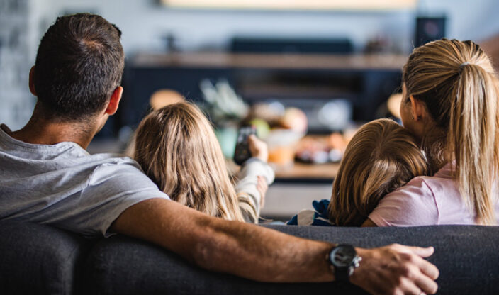 Familie sitzt auf der Couch und schaut fern