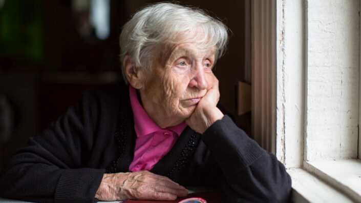 Rentnerin schaut aus Fenster