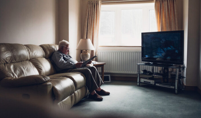 Rentner sitzt vor großem Fernseher