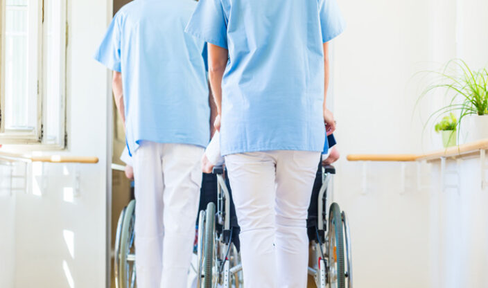Pfleger schieben zwei Rollstühle