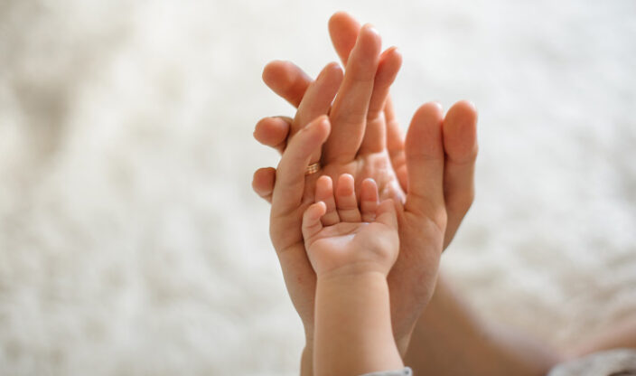 Hände von Eltern und Baby