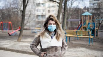 Frau mit Maske vor Spielplatz