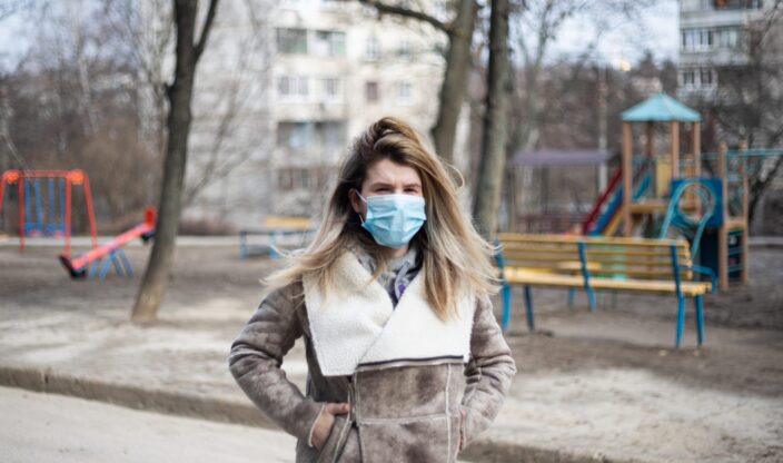 Frau mit Maske vor Spielplatz