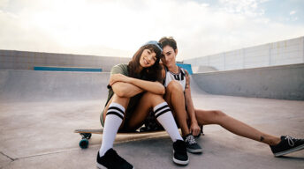 Zwei Frauen sitzen auf Longboard
